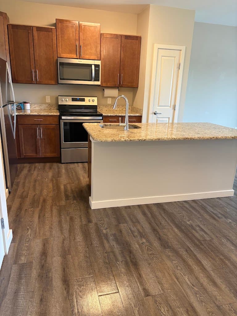 Spotless residential kitchen with granite island and stainless steel appliances after cleaning